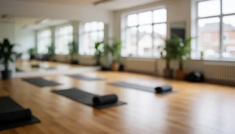 Fond de studio de yoga avec sols en bois, plantes et grandes fenêtres, idéal pour les textes sur le bien-être.
