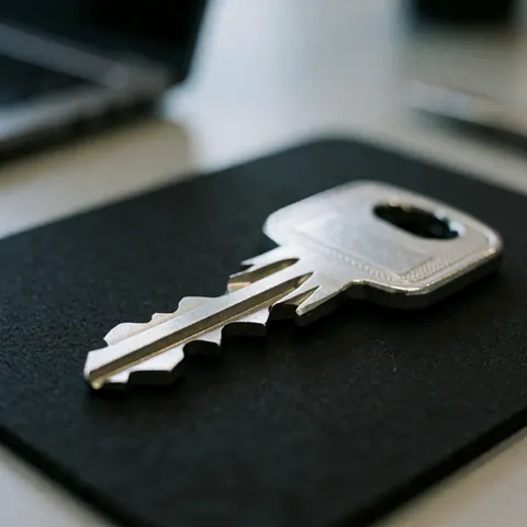 Clé de sécurité métallique avec détails en relief sur un fond noir mat, idéale pour les professionnels de la serrurerie.