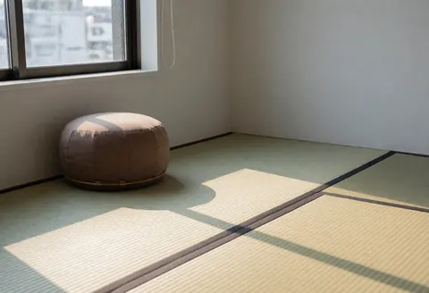 Un coussin zafu posé sur un tatami dans une salle de thérapie, éclairée par la lumière naturelle de l'après-midi, créant une ambiance calme et professionnelle.