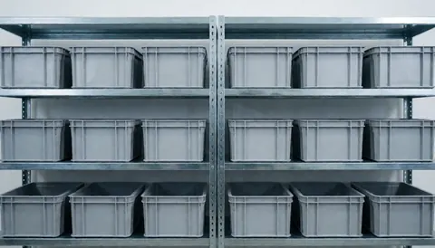 Des étagères industrielles en métal contenant des boîtes en plastique grises, offrant un fond propre et ordonné pour du texte sur la réparation de téléviseurs.