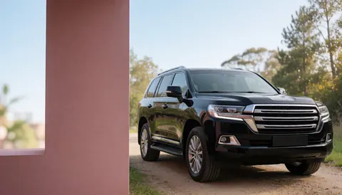 Suv noir moderne stationné sur un chemin de terre avec un mur rose en arrière-plan, idéal pour la vente de véhicules.