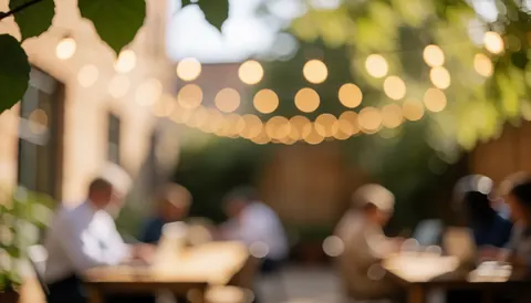 Arrière-plan flou de terrasse avec lumières chaudes, feuilles vertes et tables, idéal pour un cours d'espagnol.