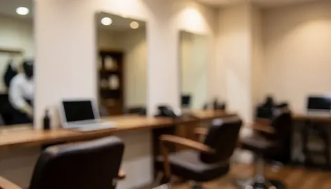 Arrière-plan flou d'un salon de coiffure avec chaises, miroirs et tables de travail, idéal pour du texte ou la couverture d'une entreprise.