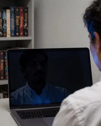 Une personne utilise un ordinateur portable devant une étagère remplie de livres de fantasy, évoquant une scène d'écriture créative en bureau.