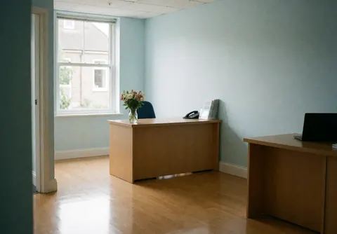 Réception de clinique avec table en bois, fleurs fraîches et murs bleus, ambiance propre et accueillante.