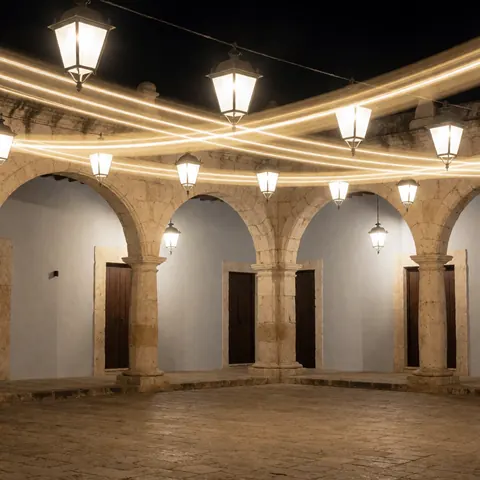 Place coloniale avec des arcs en pierre et des lanternes éclairées la nuit, idéale pour un fond de texte professionnel.