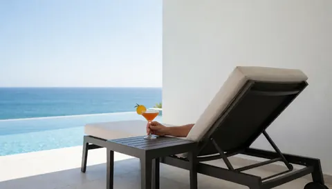 Chaise de piscine avec un cocktail et une vue sur la mer, idéale pour un site web de resort.
