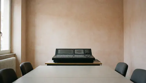 Console de mixage numérique dans une salle avec murs en terre cuite et lumière naturelle, idéale pour la page d'accueil de services audio professionnels.