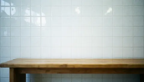 Banc en bois avec grain visible devant un mur de carreaux blancs brillants, servant de fond pour du texte dans un parc aquatique.