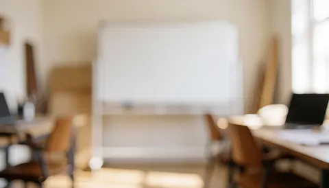 Arrière-plan flou d'une salle de cours de rédaction avec tableau blanc, chaises et tables en bois, éclairage chaud et diffus, idéal pour superposer du texte.