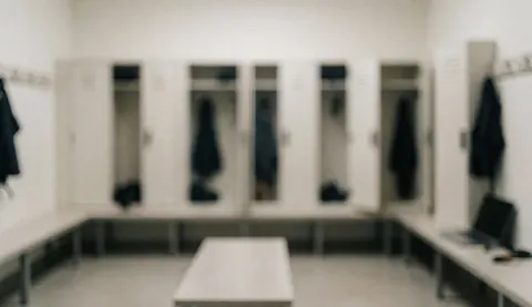 Vestiaire d'arts martiaux avec des casiers blancs, des bancs et une lumière diffuse, idéal pour un texte sur l'entraînement.