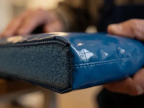 Gros plan sur le coin d'un tapis de gymnastique bleu montrant la texture de la mousse intérieure, les coutures et un reflet de fenêtre sur la surface.