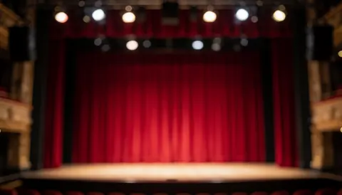 Scène de théâtre vide avec rideaux rouges et lumières bokeh, idéale pour textes promotionnels de spectacles.
