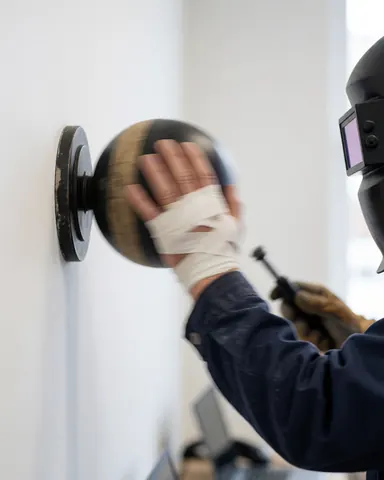 Une main bandée frappe un speedball sur un mur blanc. Équipement de boxe visible, illustrant l'entraînement sportif et le mouvement dynamique.