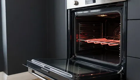 Four de cuisine avec élément chauffant allumé, porte ouverte, parois gris anthracite, intérieur propre et lumineux, idéal pour la réparation d'appareils électroménagers.