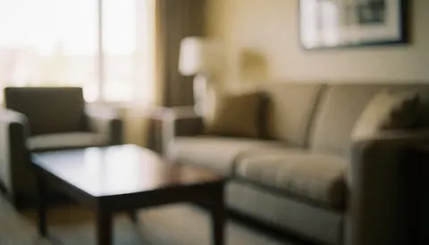 Vue d'un salon d'appartement-hôtel avec canapé et table basse, éclairage naturel et murs neutres, espace calme et confortable.