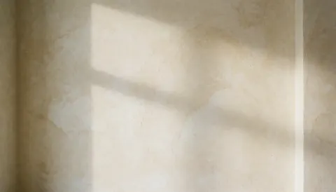 Mur à texture douce en tons crème avec lumière diffuse et ombre de fenêtre, idéal comme arrière-plan pour textes dans des cafés ou espaces décoratifs.