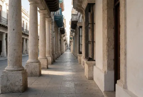 Rue étroite pavée avec colonnes coloniales en pierre, architecture historique dans un centre ancien, idéale pour les vélos-taxis.