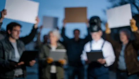 Arrière-plan flou de manifestation au crépuscule avec des silhouettes tenant des pancartes, dans des tons bleus et gris, adapté pour superposer du texte.