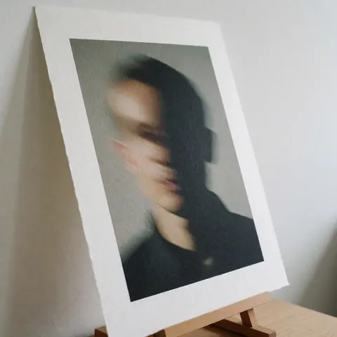 Photographie artistique avec effet d'ombre, imprimée sur papier texturé et posée sur un support en bois, idéale pour les photographes de portrait.