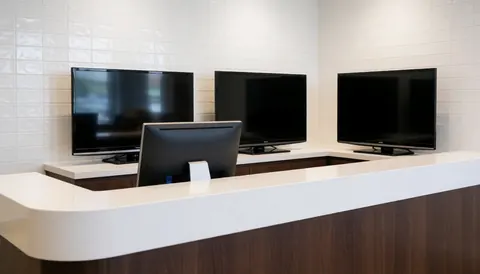 Comptoir moderne avec trois téléviseurs réparés, mur de carreaux blancs, surface propre et brillante, idéal pour réparation de téléviseurs