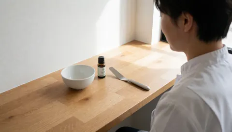 Un professionnel de la peau prépare des produits sur une table en bois avec une lumière naturelle, montrant des outils et un environnement propre.