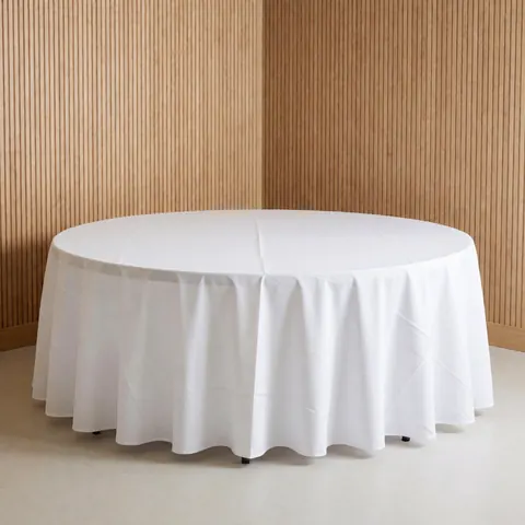 Table ronde couverte d'une nappe blanche posée sur un sol clair, devant un mur en lattes de bois, éclairage professionnel pour location de mobilier événementiel.