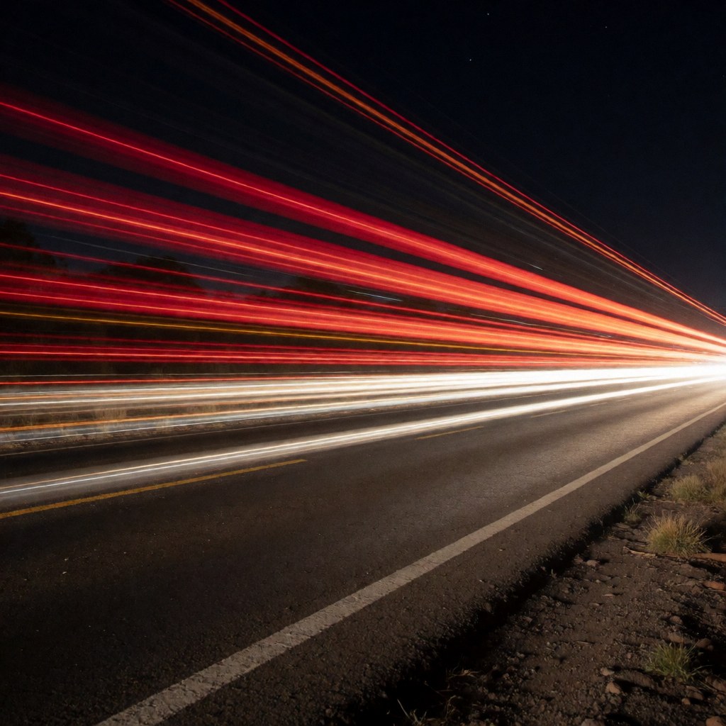 Photographie nocturne montrant des traînées lumineuses rouges et blanches de véhicules en mouvement sur une route, idéale pour un fonds textuel.