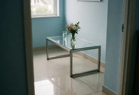 Salle d'attente moderne avec table en verre, fleurs fraîches et murs bleus, idéale pour un garage automobile.