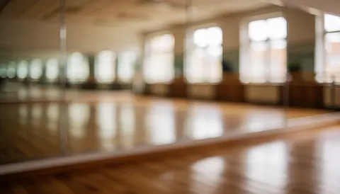 Fond de studio de gymnastique avec grands miroirs, sol en bois et fenêtres, idéal pour du texte sur les cours de gymnastique.