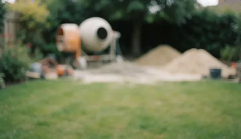 Arrière-plan flou d'un jardin montrant un malaxeur de béton et des tas de sable, idéal pour des textes liés à l'installation de piscines