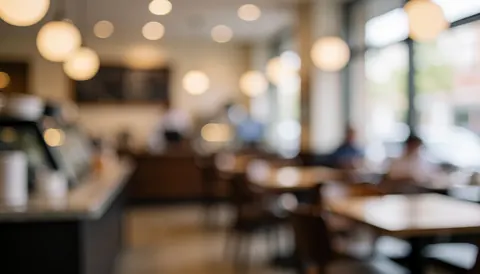 Arrière-plan de café avec tables, chaises et lumières suspendues floues, idéal pour texte ou logo