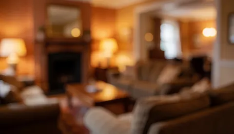 Arrière-plan chaleureux et flou d'un salon d'auberge avec cheminée, canapés et éclairage d'ambiance, idéal pour superposer du texte.