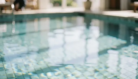 Fond de piscine avec carreaux et reflets de lumière, idéal pour les textes de services de plage et d'expériences aquatiques.