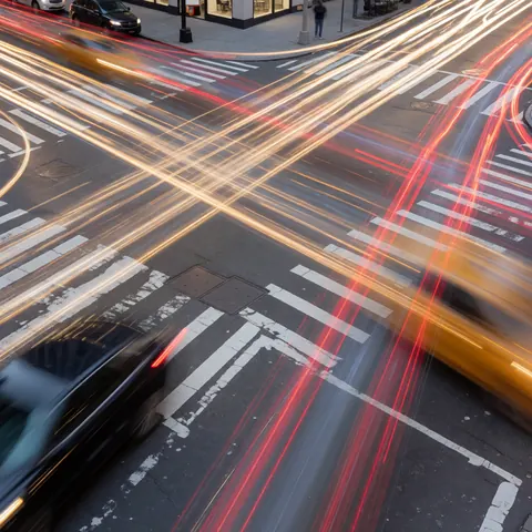 Longue exposition d'une intersection de rue en ville avec des traînées de lumière de véhicules, idéale pour les entreprises de photographie dynamique.