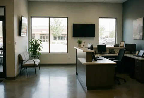 Réception de bureau moderne avec bureau, banc d'attente et grandes fenêtres laissant entrer la lumière naturelle.