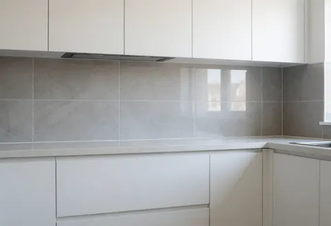 Cuisine contemporaine équipée de carrelage gris, de placards blancs et d'une fenêtre laissant entrer la lumière naturelle, idéale pour un carreleur.
