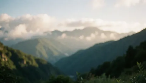 Paysage de montagnes avec des nuages et une lumière chaude, idéal pour un arrière-plan de texte concernant un entraîneur de vélo de montagne.