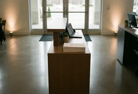 Réception moderne avec bureau en bois, sol poli et éclairage chaleureux, idéale pour des événements professionnels.