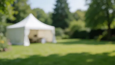 Fond de jardin avec une marquise blanche, de l'herbe verte et des arbres, idéal pour les événements en plein air et les textes commerciaux