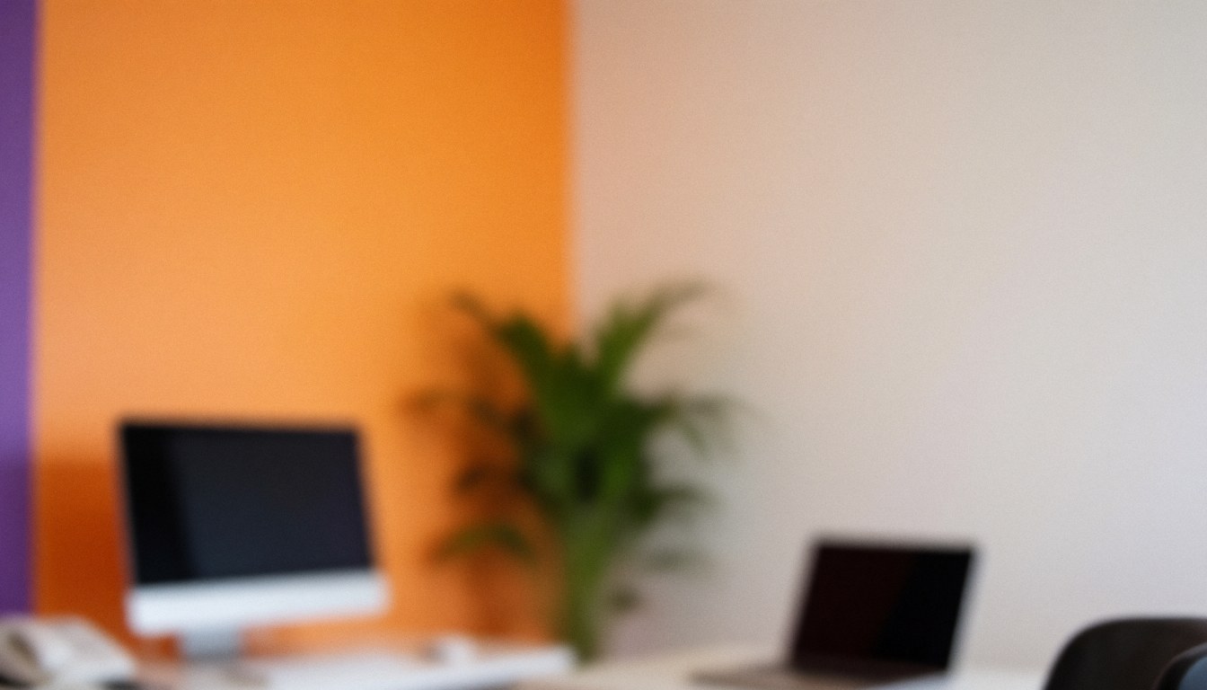 Espace de travail moderne avec murs orange et violet, ordinateur, ordinateur portable et plante, idéal pour superposer du texte.