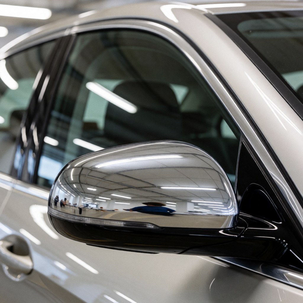 Rétroviseur chromé brillant et vitre propre d'une voiture blanche dans un garage éclairé par des néons, évoquant les services de stationnement.