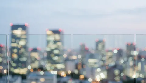 Vitrine transparente en verre avec un arrière-plan de ville au coucher du soleil, idéal pour un fond de texte commercial.