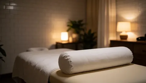Lit de massage blanc dans une salle de spa avec murs carrelés blancs et éclairage chaleureux, idéal pour une page d'accueil de site web.
