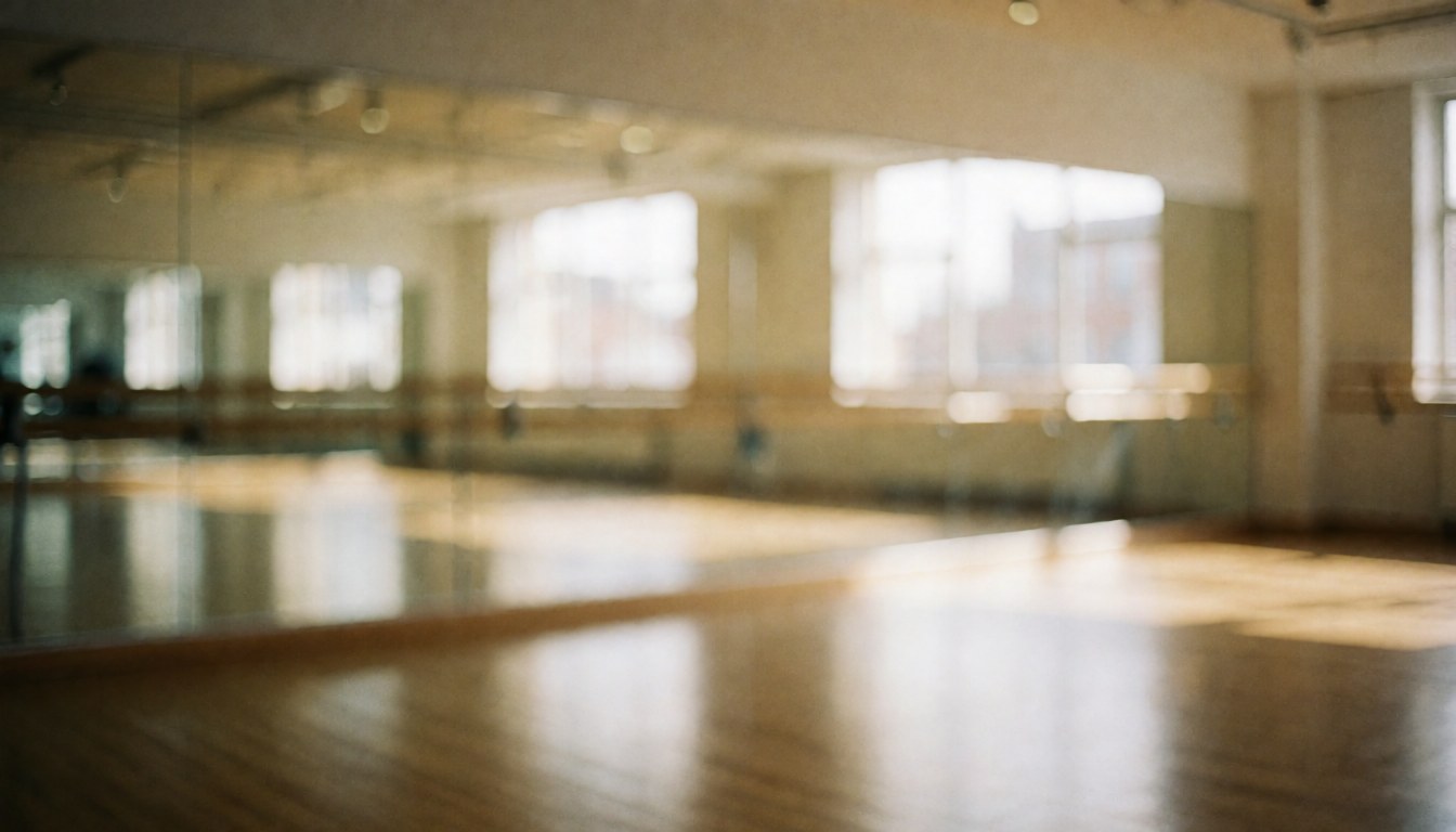 Intérieur d'un studio de danse moderne avec grands miroirs, sol en bois clair et barres de danse, offrant un fond neutre et lumineux idéal pour ajouter du texte.