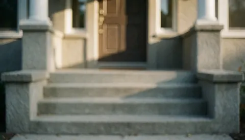 Escaliers en béton menant à une porte d'entrée avec lumière de coucher de soleil, idéal pour fond de texte de réparation d'escaliers.