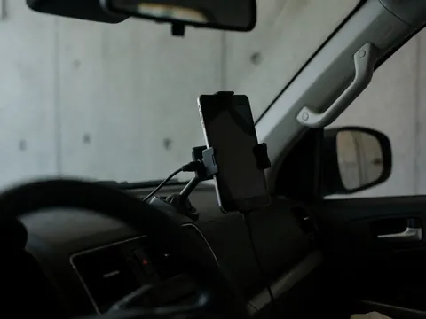 Support de téléphone fixé sur le tableau de bord avec des câbles organisés, fond en béton, adapté au transport public.