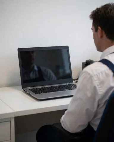 Un technicien examine un ordinateur portable sur une table dans un bureau professionnel aux murs blancs et à l'éclairage doux.