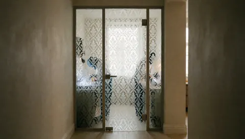 Porte en verre gravé ornée d'un motif décoratif dans un couloir aux murs neutres et à l'éclairage doux, idéale pour une vitrerie.