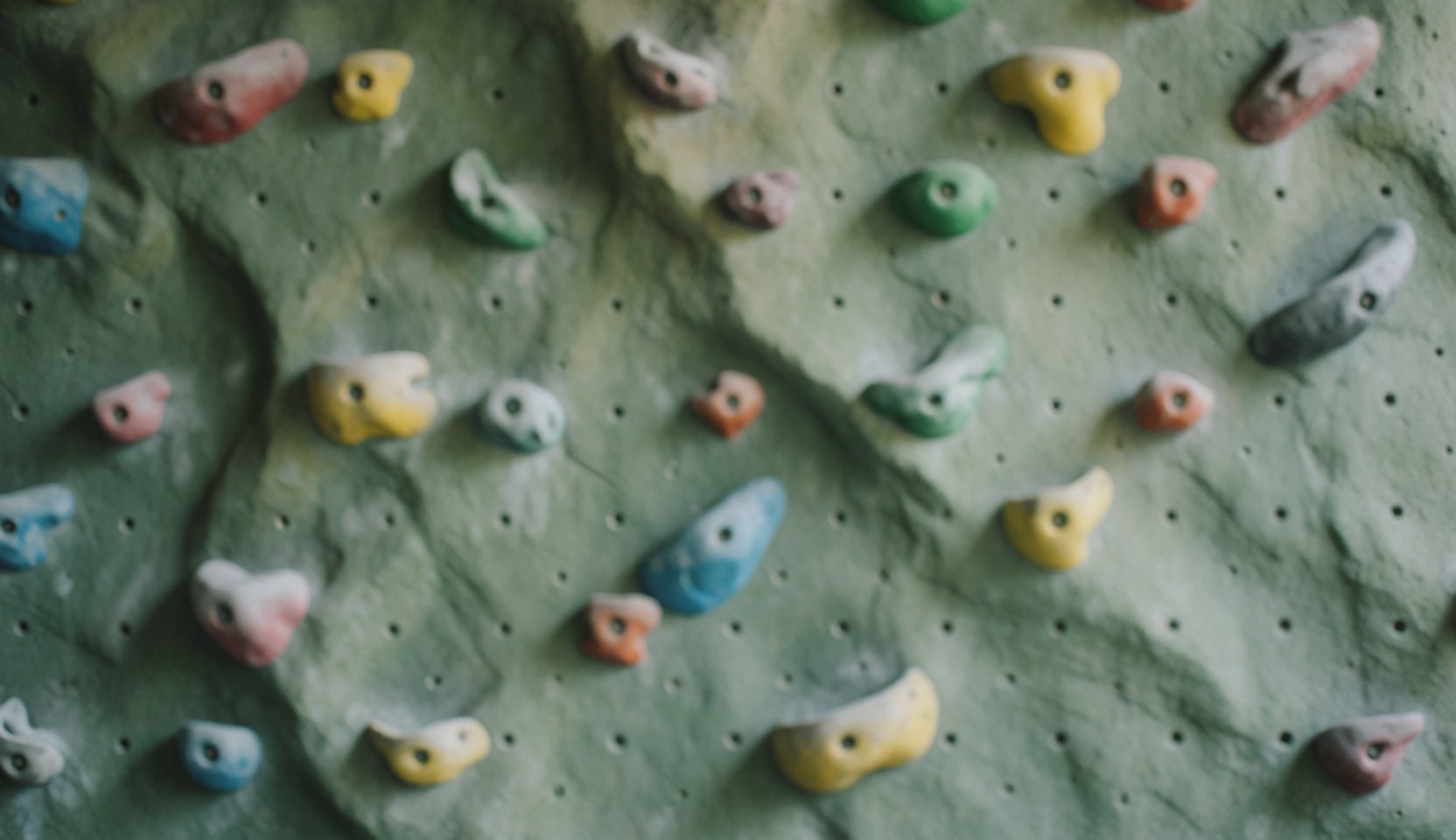 Mur d'escalade artificiel avec des prises colorées et une texture de roche, fond idéal pour les textes d'un parc d'aventure.